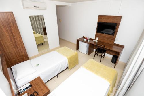 塞拉Hotel Jardins的客房设有两张床、一张桌子和一台电视。