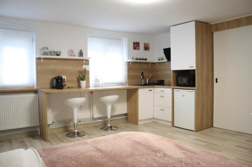布拉索夫Apartment BIANCA的厨房配有白色橱柜和带凳子的台面
