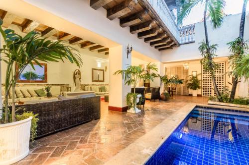 卡塔赫纳Hotel Casa la Tablada的一座室内游泳池,位于一座带浴缸和棕榈树的房屋内