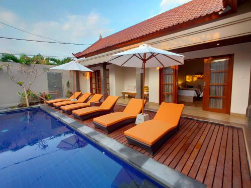 塞米亚克玛哈巴厘岛塔曼阿美萨别墅的一个带橙色躺椅和遮阳伞的游泳池