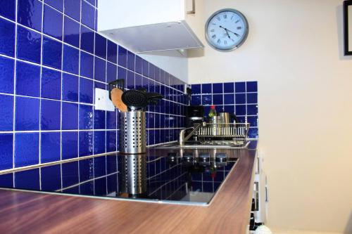 RushThe Beachfront Retreat的蓝色瓷砖厨房配有水槽和时钟