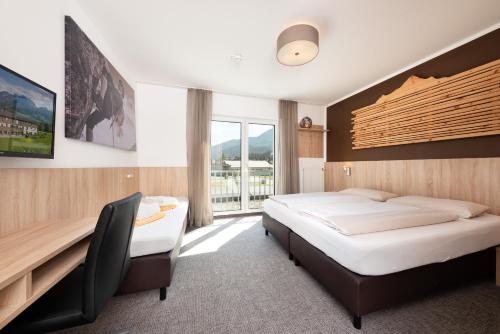 霍赫菲尔岑Fairhotel Hochfilzen B&B的一间卧室设有两张床、一张桌子和一个窗口。
