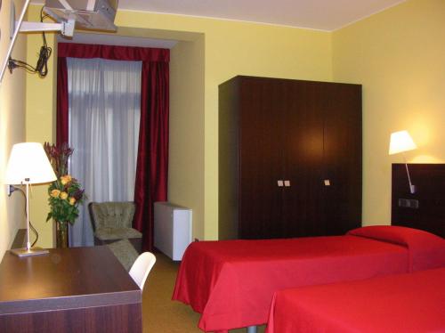 帕多瓦艾尔伯格威尔第酒店的酒店客房,配有两张床、一张桌子和一把椅子