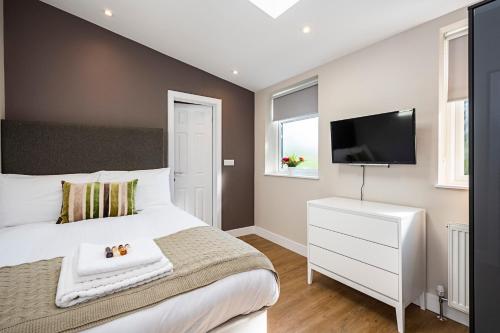 伦敦South Woodford 2 Bed En-Suite House的卧室配有白色的床和平面电视。