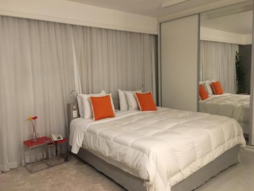 圣保罗Loft Confortável e Moderno的卧室配有带橙色枕头的大型白色床