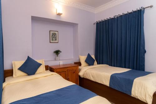 博卡拉Gaurishankar Backpackers hostel的一间卧室配有两张床和蓝色窗帘