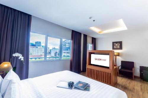 胡志明市Saigon Hotel的一间酒店客房,配有一张床和一台电视