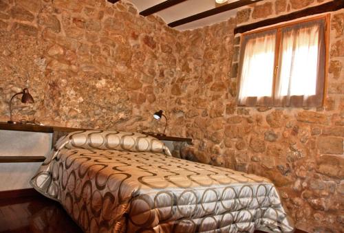 奥尔塔-德圣胡安La Serra Rural的卧室配有一张石墙床