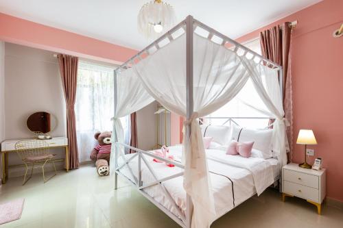 三亚夏树客栈（原船长青年旅社）的一间卧室配有一张带粉红色墙壁的天蓬床。