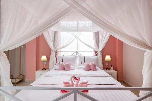 三亚夏树客栈（原船长青年旅社）的卧室配有白色床、粉红色枕头和窗户