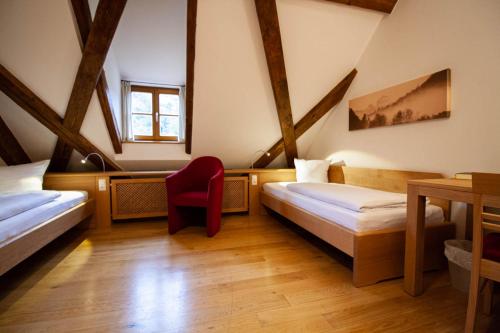 凯尔海姆圣乔治维尔腾伯格旅馆的一间设有两张床和红色椅子的房间