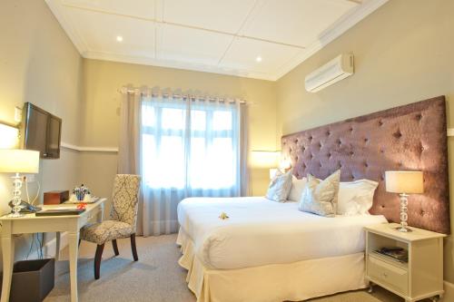德班圣詹姆斯威尼斯旅馆的一间卧室配有一张床、一张书桌和一个窗户。