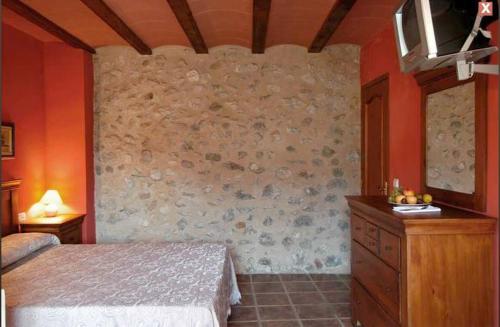 Vall de Ebo琳芬山沟乡村酒店的一间卧室设有一张床和石墙