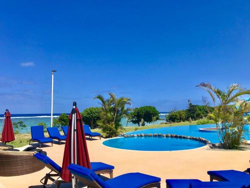 YanduaYadua Bay Resort & Villas的海滩上的游泳池配有椅子和遮阳伞