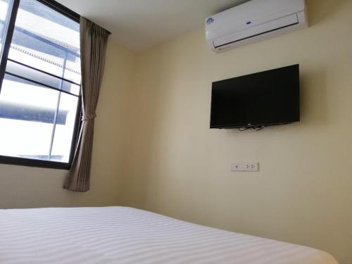曼谷The Marble Hostel的卧室配有一张床和壁挂式平面电视。