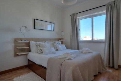 埃斯托利尔Sunny Monte Estoril的白色卧室设有一张大床和窗户