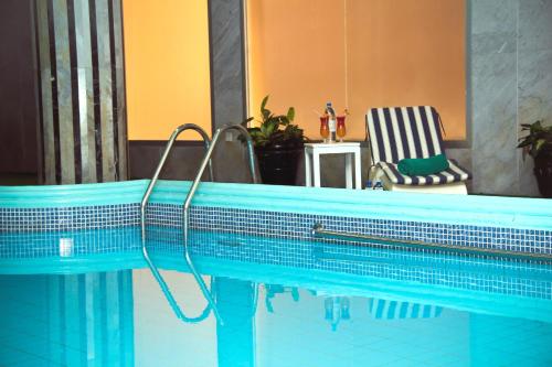 沙迦诺瓦公园酒店的蓝色游泳池旁设有椅子