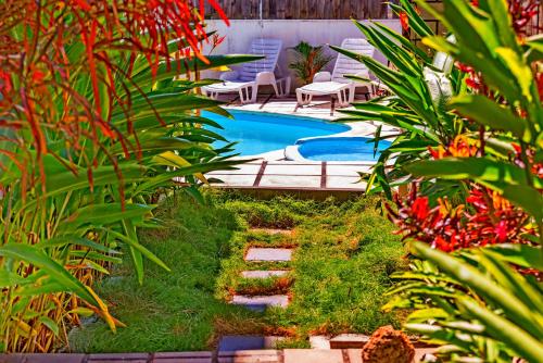 特鲁欧克比赫斯Villa les bananniers的花园设有游泳池、椅子和植物