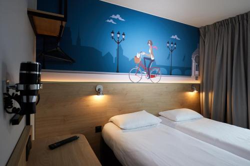 拉沙佩勒圣梅曼KYRIAD DIRECT Orleans - La Chapelle St Mesmin的一间房间,里面设有一张床,在自行车上画了一位女人