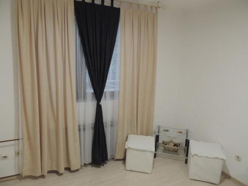 萨拉热窝APARTMAN AZRA的客房设有带窗帘的窗户和2张凳子