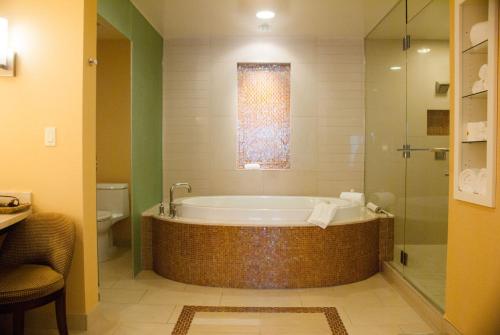 兰乔米拉日Agua Caliente Casino Rancho Mirage的带浴缸和玻璃淋浴间的浴室。