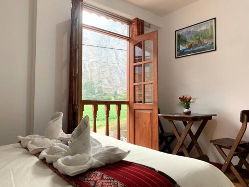 奥兰太坦波Inka Khawarina Tambo Lodge的一间卧室配有一张带毛巾的床和窗户。
