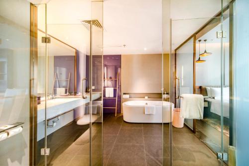 海口海口美兰绿地铂骊Q酒店的带浴缸和玻璃淋浴间的浴室。
