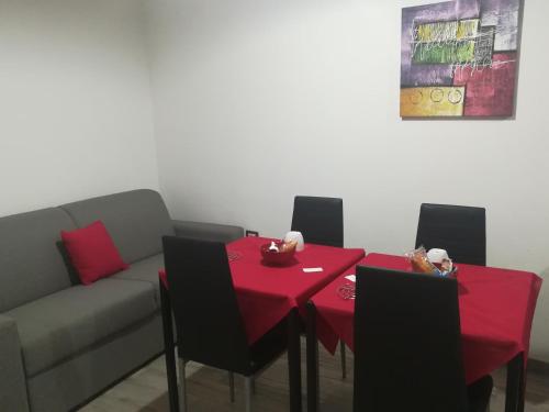 SestuDomos Loru的一间用餐室,配有红色的桌子和椅子以及一张沙发