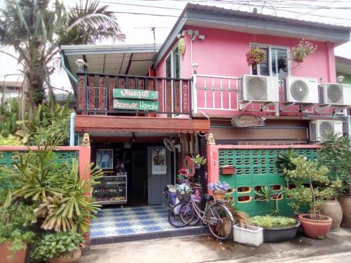 班敦孟Ban Kru Ae mixed dorm的一座粉红色的房子,前面停放着自行车
