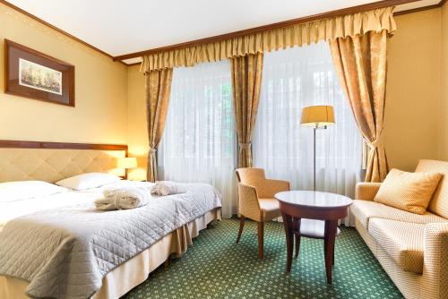 什切青帕克酒店的酒店客房,配有床、桌子和椅子
