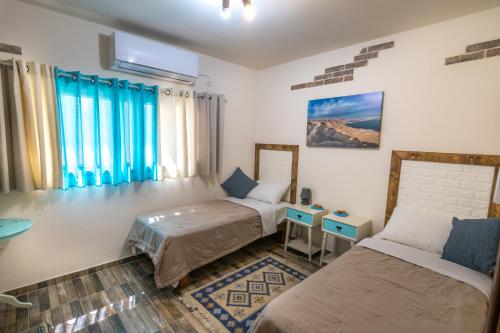阿拉德Desert Picture的客房设有两张床、一张桌子和窗户。