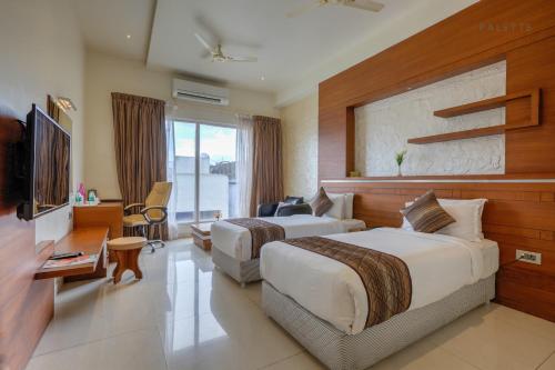 纳盖科伊尔Hotel Pioneer Grand Palace的酒店客房设有两张床和电视。