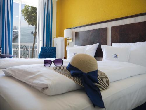 梅尔斯堡Hotel & Gästehaus Seehof的酒店客房,配有带帽子和太阳镜的床