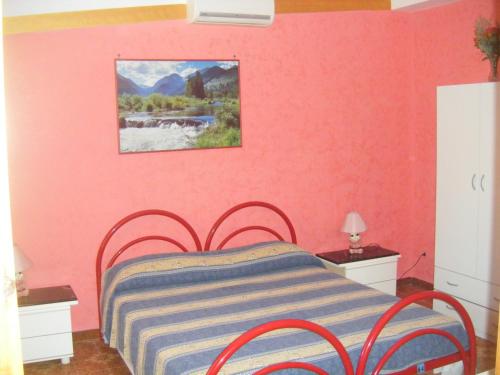 马萨夫拉Villa Robinia的一间卧室配有一张粉红色墙壁的床