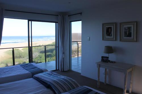 蚝湾Oyster bay beach house的一间带两张床的卧室和一个海景阳台