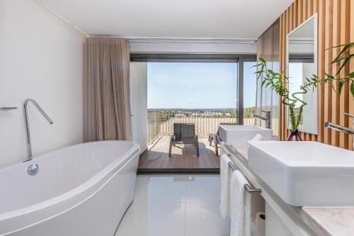 Montes de CimaAlgarve Race Resort - Hotel的一间设有两个盥洗盆和浴缸的浴室,享有美景。