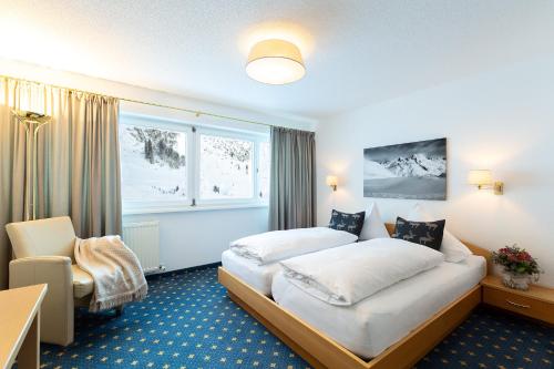 莱赫阿尔贝格Chalet Schneekristall的配有一张床和一把椅子的酒店客房