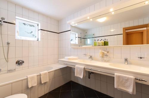 莱赫阿尔贝格Chalet Schneekristall的浴室设有2个水槽、浴缸和镜子