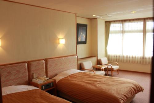 那智胜浦町Manseiro的酒店客房设有两张床和窗户。