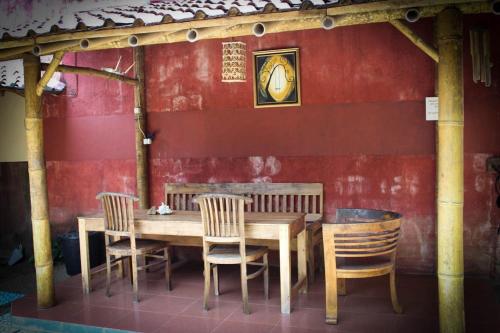 巴芝丹哈利斯海滨之家2号帕西坦民宿的红色墙前的一张木桌和椅子