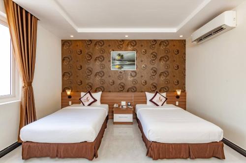 富国Phung Hung Boutique Hotel的酒店客房带两张床和一面墙