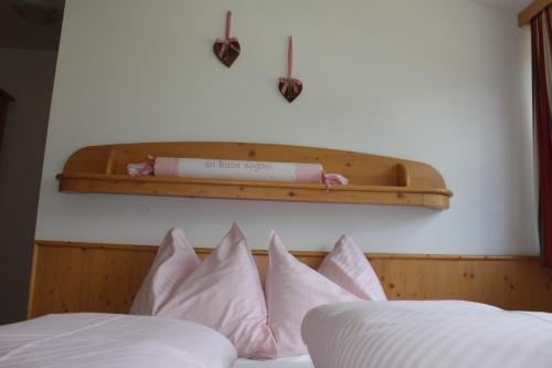 布鲁尼科Appartementhaus Lechnerhof的一张带粉红色枕头的床和上面的架子