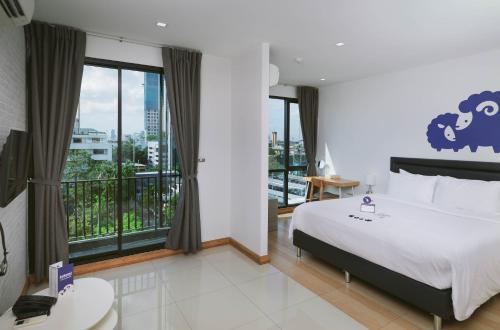 曼谷Kokotel Bangkok Sukhumvit 50 - SHA Extra Plus的一间卧室设有一张大床和一个大窗户