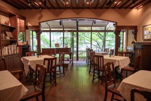 神户有马温泉陶泉御所坊酒店的餐厅设有桌椅和大窗户。