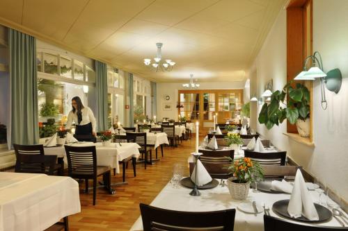 因特拉肯美地经济酒店的站在带桌椅的餐厅的妇女