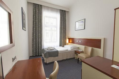 布拉格阿托斯酒店的配有一张床和一张书桌的酒店客房