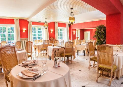 Macé乐伊尔德斯酒店的一间带桌椅和红色墙壁的餐厅