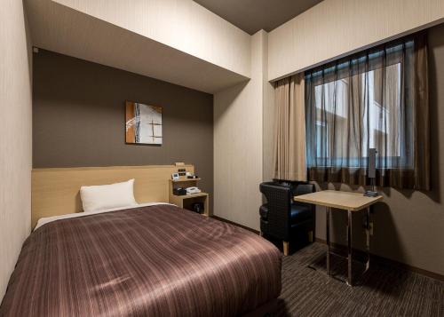 旭川旭川站前路线酒店的配有一张床、一张书桌和一扇窗户的酒店客房