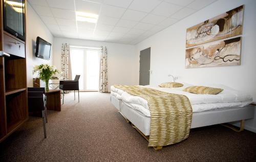 Hurup特宁格加德酒店的一间卧室配有一张床、一张书桌和一台电视