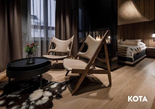 罗瓦涅米吉舍精品公寓式酒店的一间设有三把椅子、一张床和一张桌子的房间